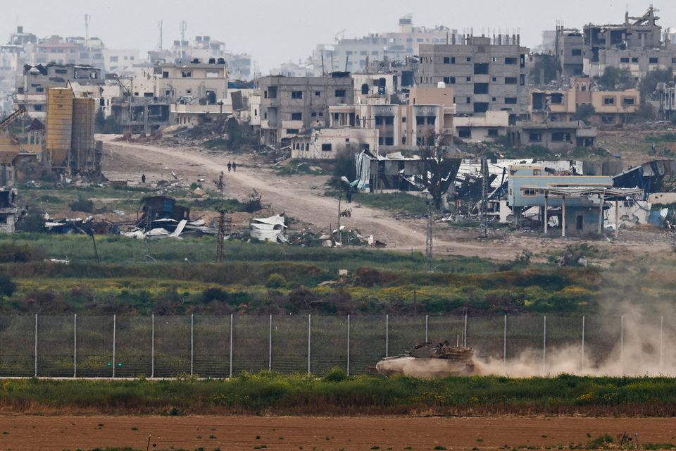 A tank maneuvers near the Israel-Gaza border on the Israeli side as people walk inside Gaza, amid the ongoing conflict between Israel and the Palestinian Islamist group Hamas, as seen from Israel, March 17, 2024. REUTERS/Amir Cohen      TPX IMAGES OF THE DAY     