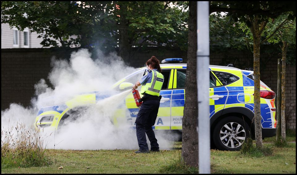 Gardaí extinguish a garda car on fire outside Coolock Garda Station. Photo: Steve Humphreys