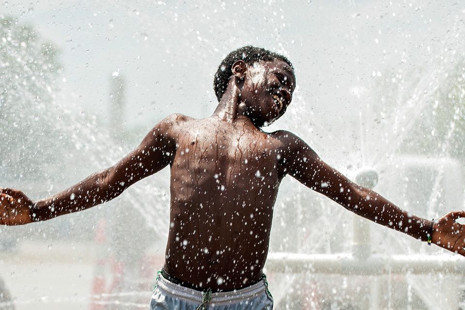 Jules Ruvoyivoyi, 13, dances in the water spray from a water hydrant powered fountain during a library water block party