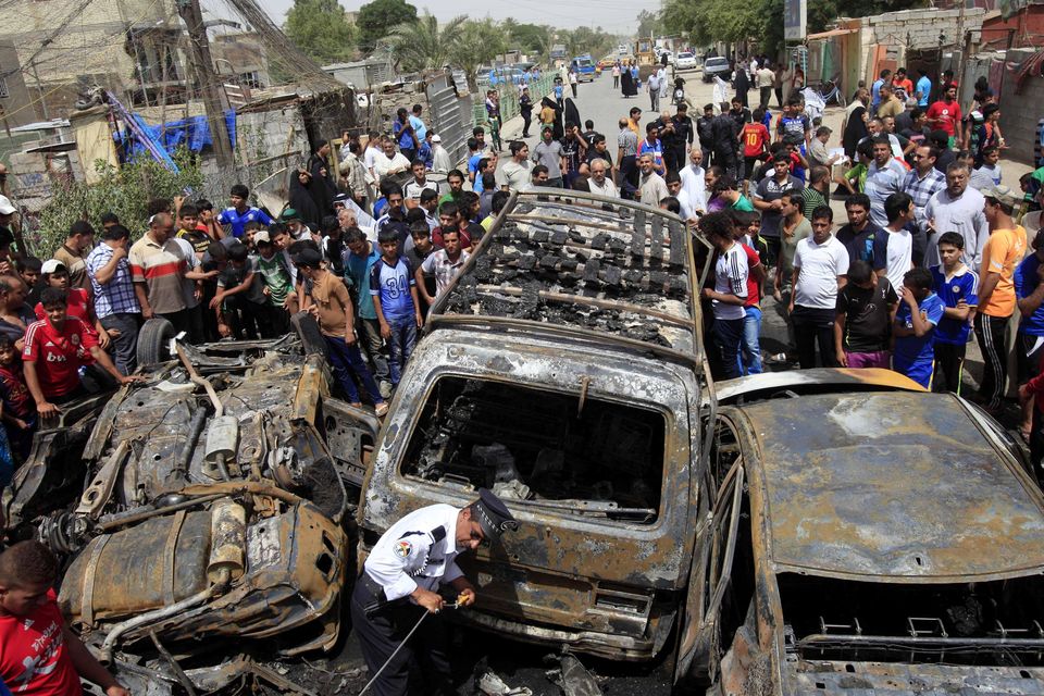 People gather at the scene of a car bomb attack in the Sadr City neighborhood in Baghdad, Iraq. A car bomb explosion in a sprawling Shiite neighborhood of Baghdad has killed and wounded dozens of people, officials said.