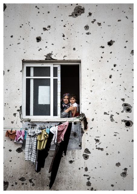 A mother hold her child while looking out from her Gaza City apartment which has been badly damaged from artillary fire and is unstable. Photo: Mark Condren