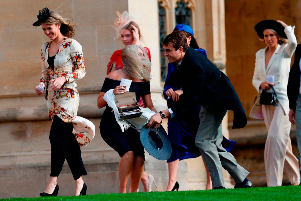 A guest stoops to collect her hat that blew off in the wind as she arrives to attend the wedding of Britain's Princess Eugenie of York to Jack Brooksbank at St George's Chapel, Windsor Castle, in Windsor, on October 12, 2018. (Photo by Adrian DENNIS / various sources / AFP)ADRIAN DENNIS/AFP/Getty Images