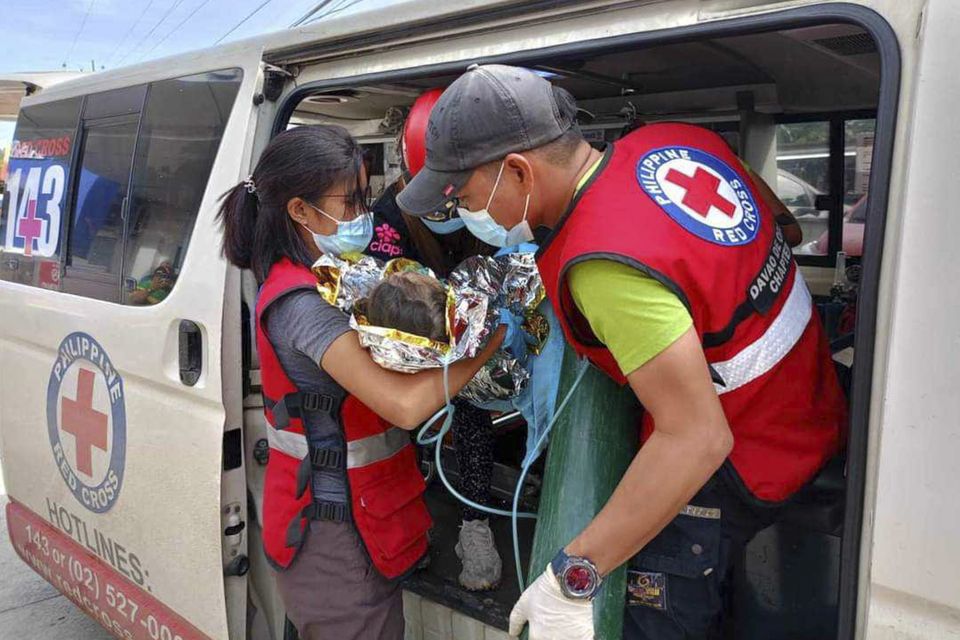 Rescuers provide medical attention to a child after the landslide (Philippine Red Cross via AP)
