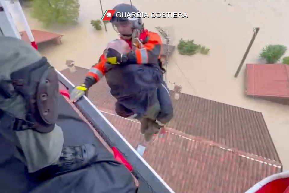 The Italian coast guard rescues a man from a roof in the town of Faenza in Emilia Romagna. Photo: ITA
