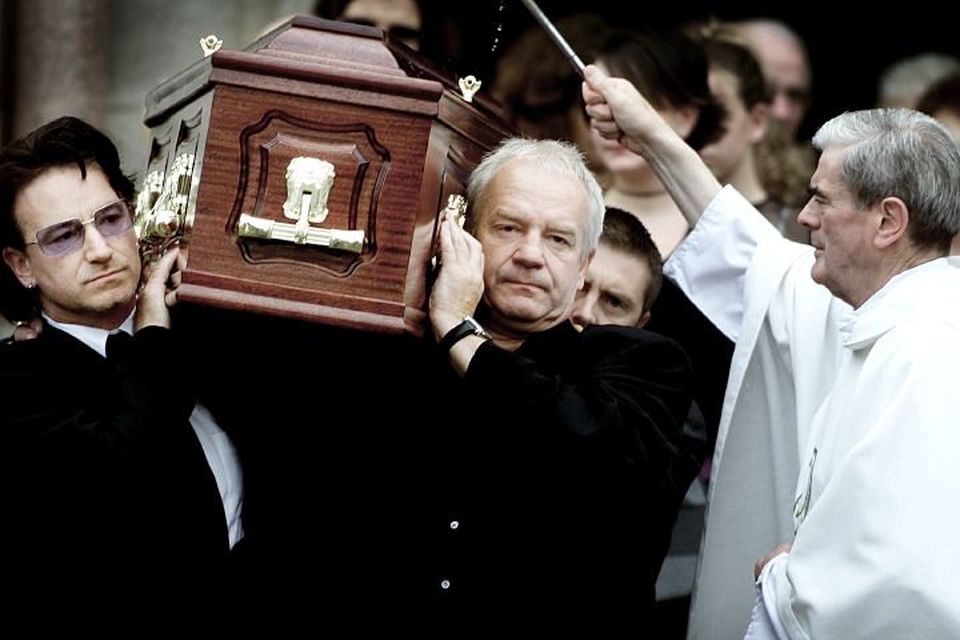 Bono and his brother Norman carry their father Bob's coffin