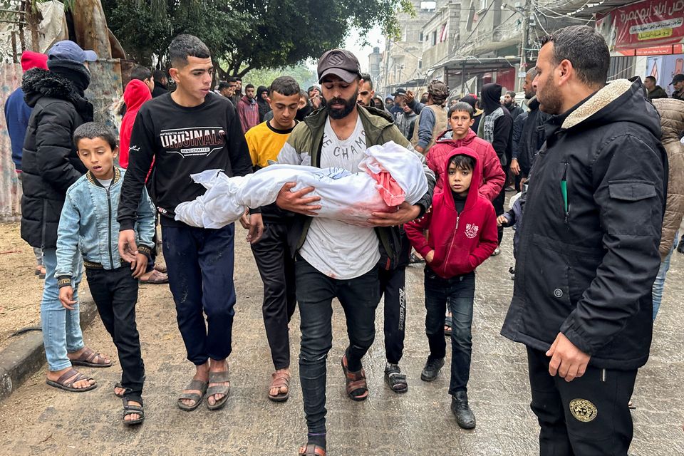 A mourner carries the body of a Palestinian child killed in Israeli strikes on houses in Rafah, Gaza. Photo: REUTERS/Fadi Shana.