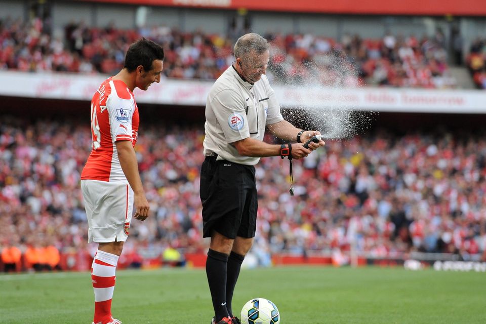 Referee Jonathan Moss gets into difficulty with his vanishing spray as Arsenal's Santi Cazorla gets an unexpected covering during the Barclays Premier League match at The Emirates Stadium, London. PRESS ASSOCIATION Photo. Picture date: Saturday August 16, 2014. See PA story SOCCER Arsenal. Photo credit should read: Andrew Matthews/PA Wire. RESTRICTIONS: Editorial use only. Maximum 45 images during a match. No video emulation or promotion as 'live'. No use in games, competitions, merchandise, betting or single club/player services. No use with unofficial audio, video, data, fixtures or club/league logos.