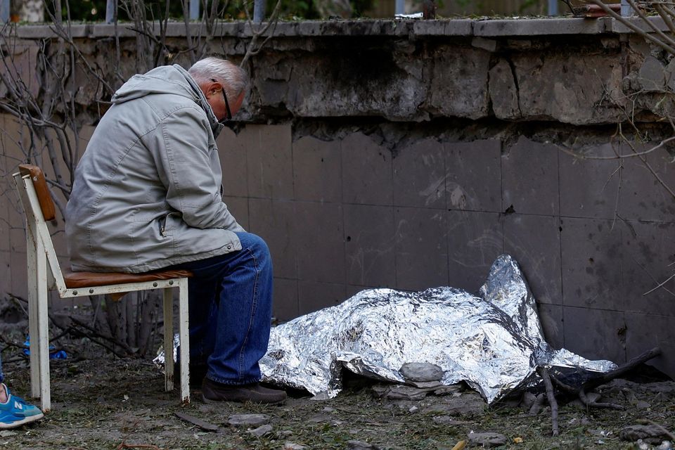A man sits next to the body of his grand- daughter who was killed during a Russian missile strike in Kyiv on Thursday, June 1. Photo: Valentyn Ogirenko /Reuters