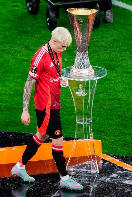 Alejandro Garnacho walks past the Europa League trophy.