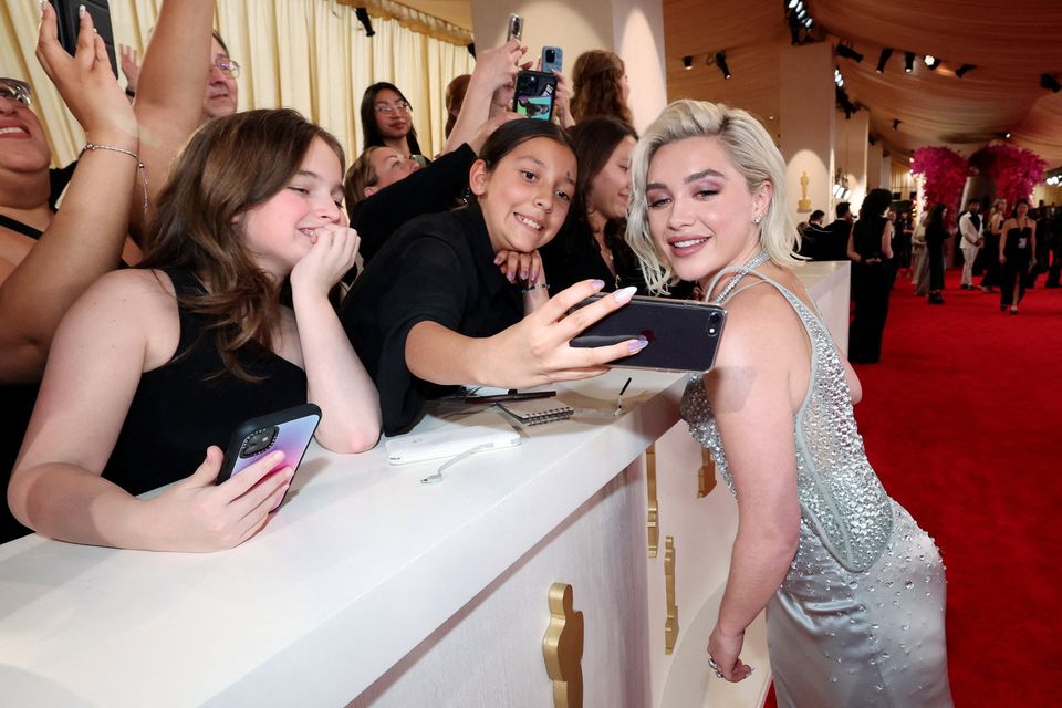 Florence Pugh poses for a photo with spectators on the red carpet during the Oscars arrivals at the 96th Academy Awards in Hollywood, Los Angeles   