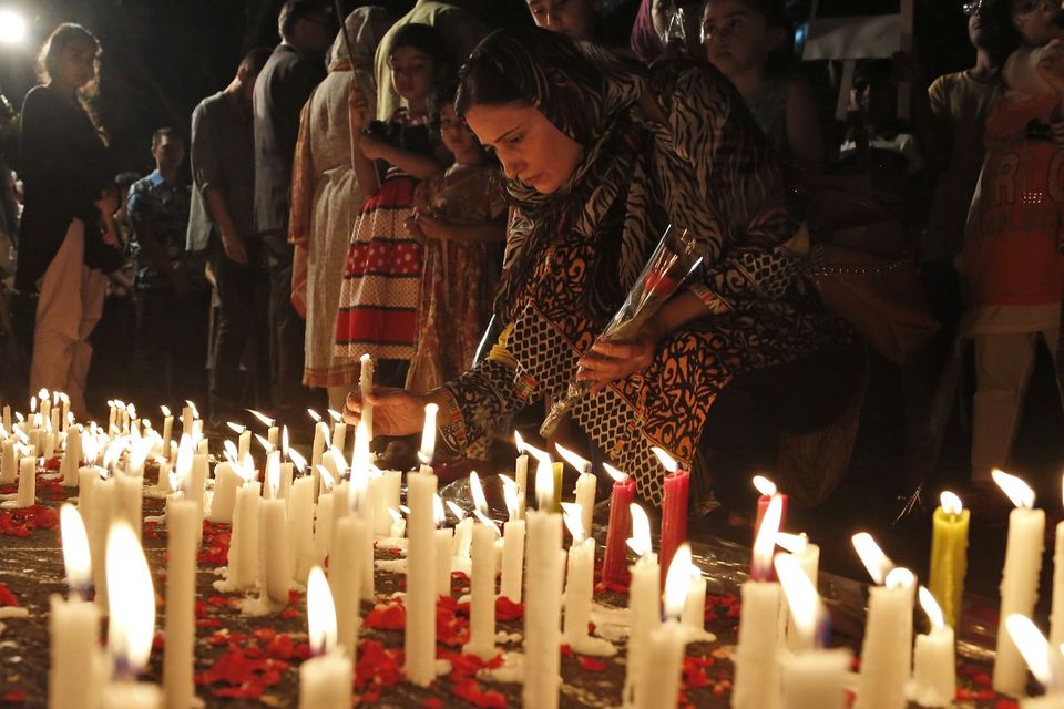 A Pakistani woman lights a candle during a vigil to pay tribute to the victims killed in Tuesday's Taliban attack on a military-run school in Peshawar, outside the Pakistani Embassy in Jakarta, Indonesia (AP)