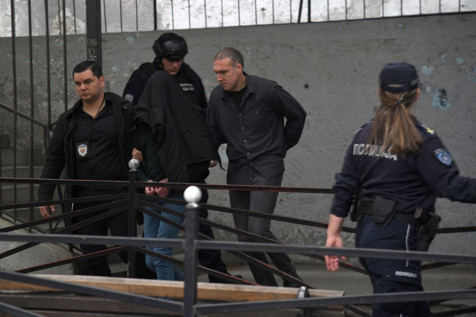 Police officers walk the suspect out of the school in Belgrade after he opened fire on other students and staff. Photos: Reuters