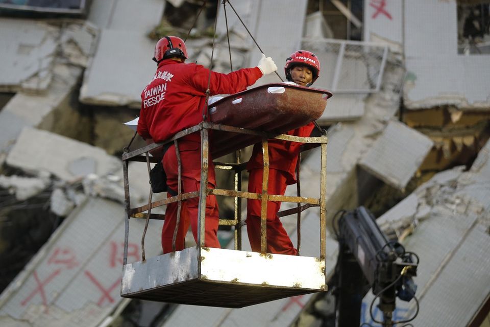 Two emergency workers carry a victim recovered from a collapsed building in Tainan (AP)