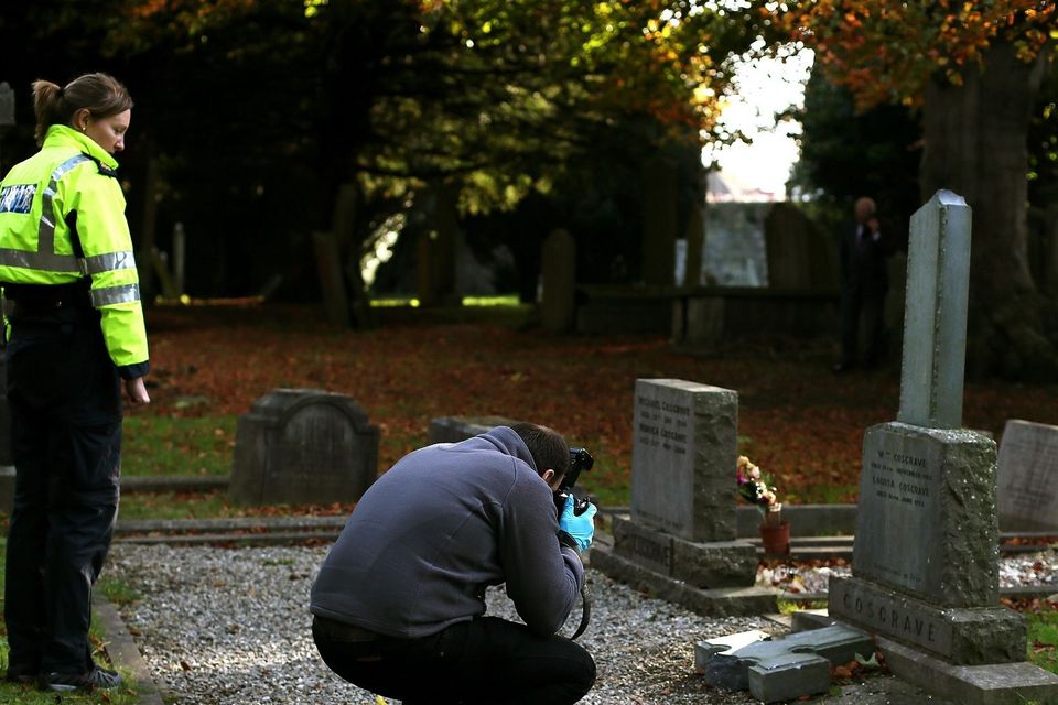 A Crimes Scene Investigator photographs the grave of William T Cosgrave