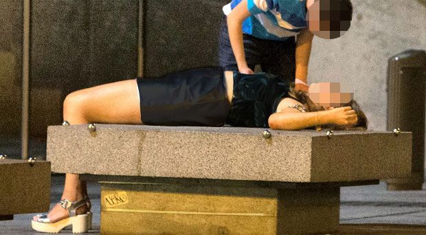 A teenage girl in a collapsed state being tended to by a friend outside the central bank