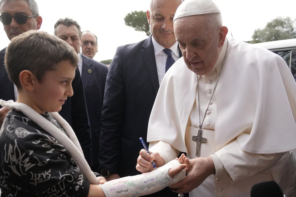 Pope Francis autographs the plaster cast of a child as he leaves the Agostino Gemelli University Hospital in Rome, Saturday, April 1, 2023 after receiving treatment for a bronchitis, The Vatican said. Francis was hospitalized on Wednesday after his public general audience in St. Peter’s Square at The Vatican. (AP Photo/Gregorio Borgia)