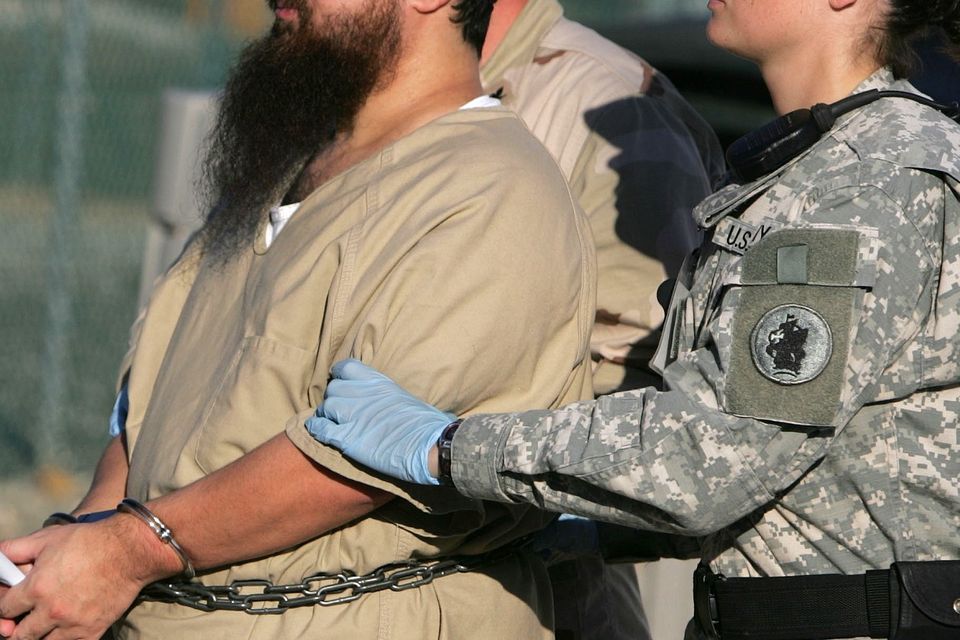 A prisoner is transported by a woman guard at Guantanamo (AP)