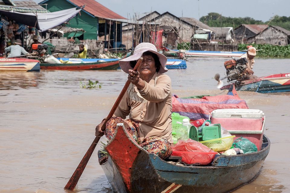 A woman rides her boat selling vegetables and supplies to the residents