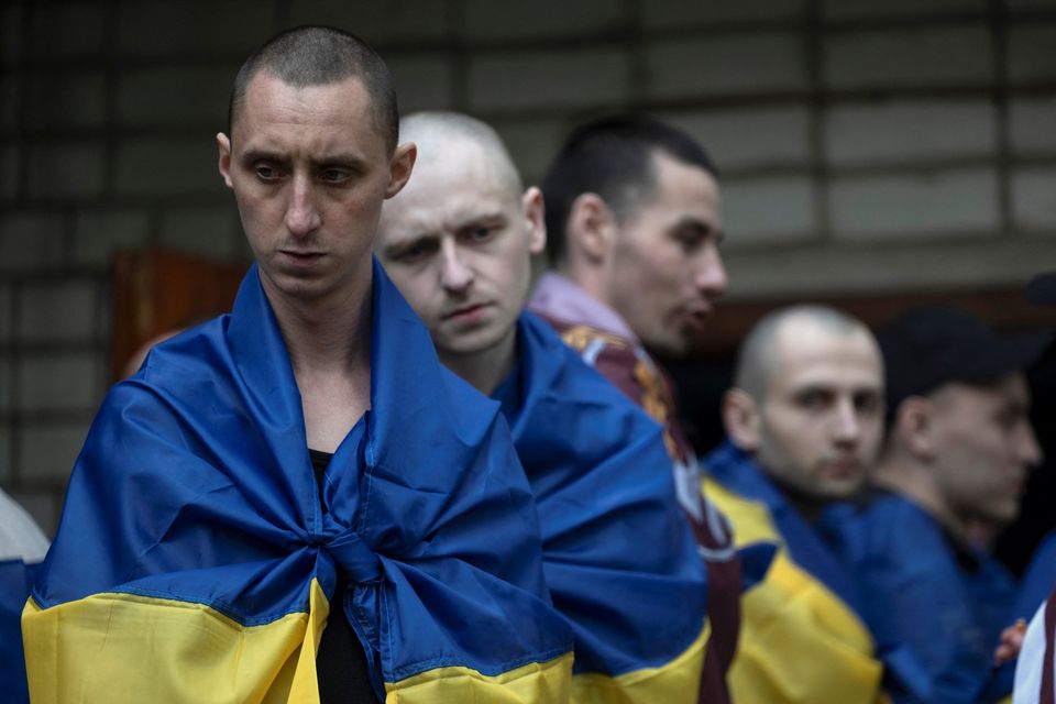 Ukrainian prisoners of war wear flags after a prisoner swap with Russia. Photo: Reuters