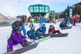 thumbnail: Snowboarders check their bindings on the slopes of Grandvalira