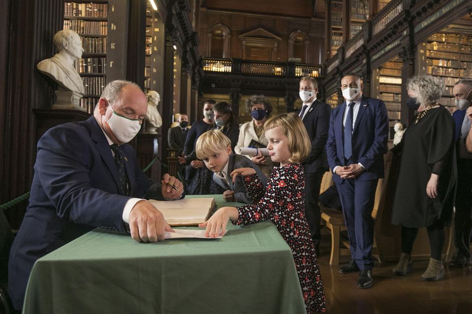 Prince Albert II of Monaco signing the visitors book in the Long Room in Trinity College his children Princess Gabriella and The Crown Prince Jacques.