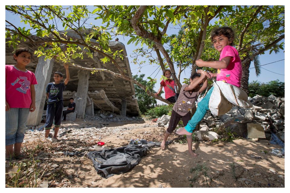 Children play on a makeshift swing in the shadow of their two-storey home which was destoryed by Israeli tanks in 2014. Photo: Mark Condren