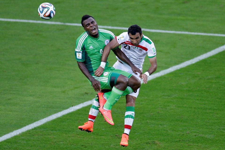 Nigeria's Reuben Gabriel, left, and Iran's Mehrdad Pooladi challenge for the ball during the group F World Cup soccer match between Iran and Nigeria