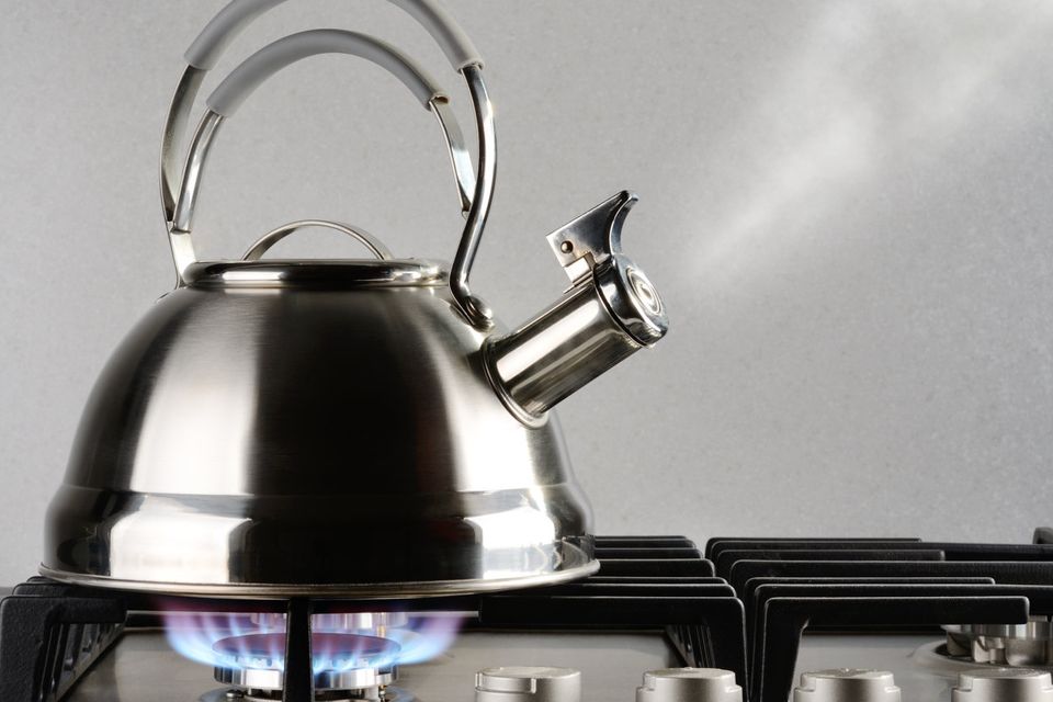 Tea kettle with boiling water on gas stove