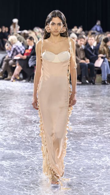 Decollete gown in rose-poudre silk-satin with corset-laced panels over an exposed corset with conical breasts in ivory cotton twill, worn with platform mules in plexiglass with pearl detail and aigu heel, and beaded cow-parsley earrings, from Jean Paul Gaultier x Simone Rocha