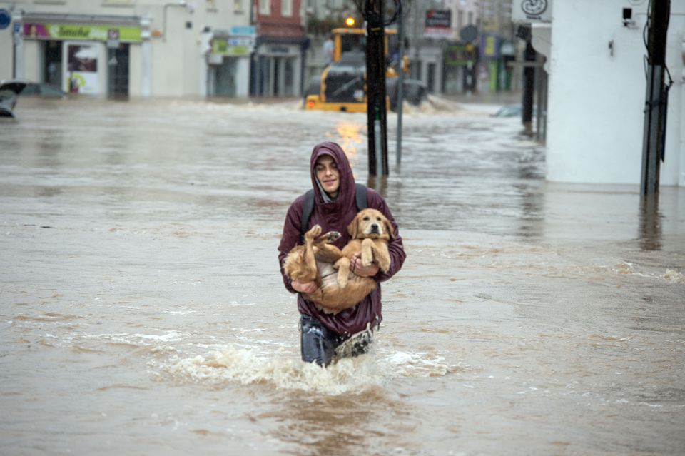 Pavel Ciechomovicz rescues his labrador Nanij from flooding on Main Street, Midelton, Co Cork. Photo: Michael Mac Sweeney/Provision