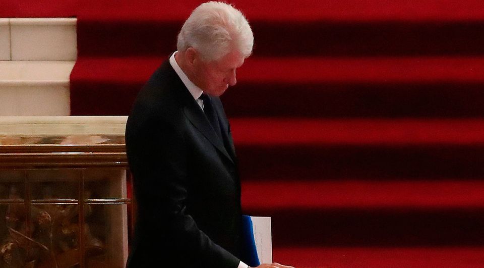 Former US president Bill Clinton pauses to touch the coffin after speaking at the funeral of Martin McGuinness in Derry. Photo: Niall Carson/PA