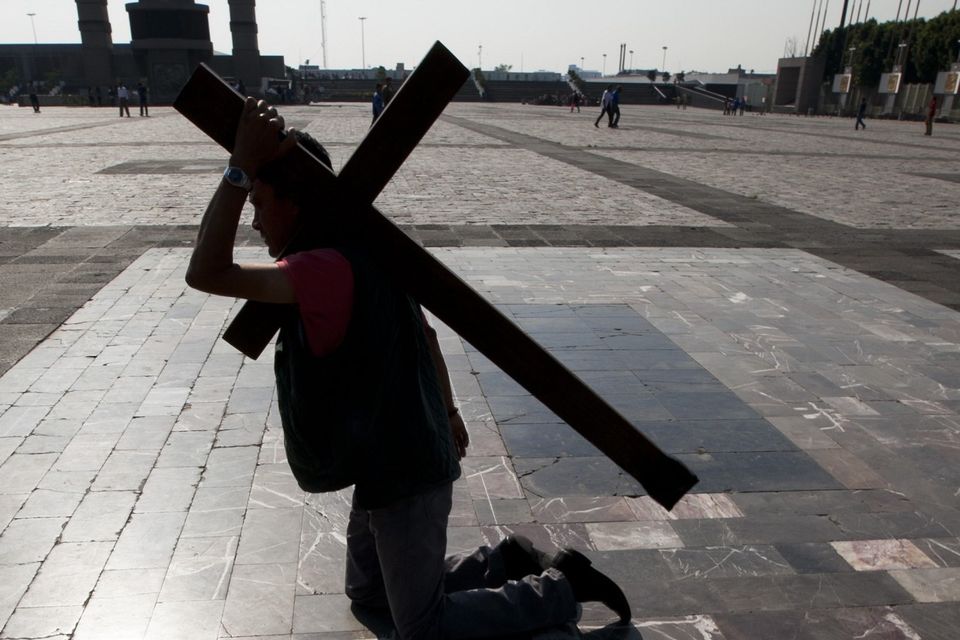 A migrant bears a cross while walking on his knees to the entrance of the Basilica of Guadalupe, in Mexico City (AP)