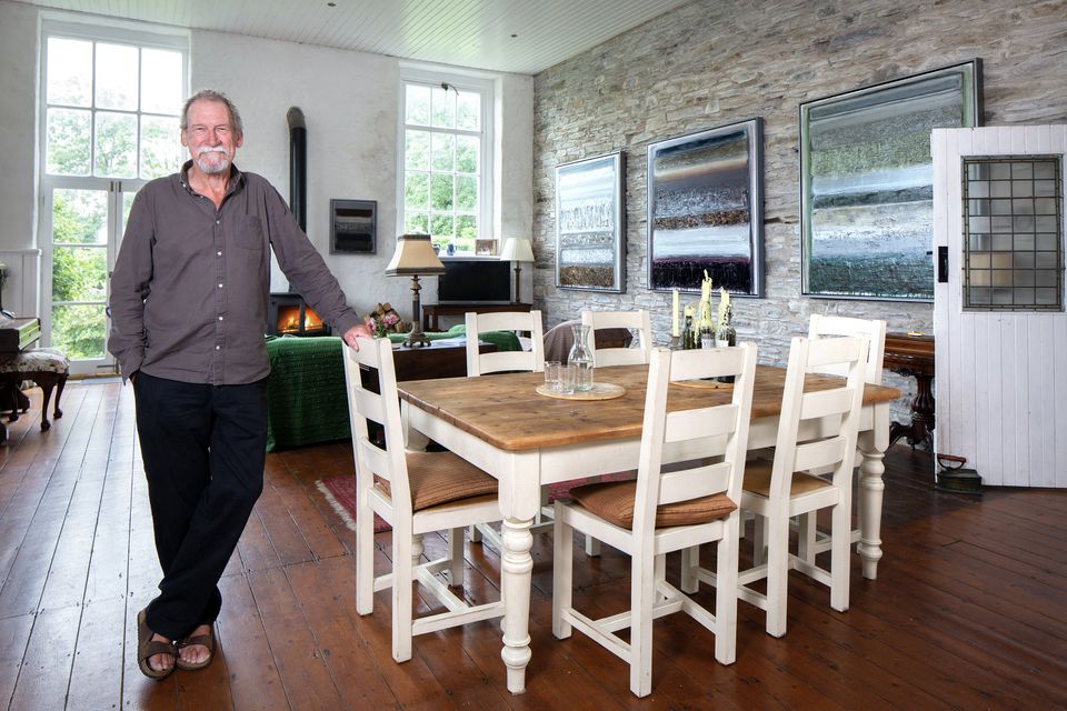 Artist Ian Humphreys in the classroom of the former schoolhouse in Rossbrin, Schull,  Co Cork. His builder John O’Brien brought some of the walls back to the original stone and Ian and his partner Sarah loved the character it adds to the room. The furniture mainly came from Sarah’s last house, while the paintings are by Ian. The middle one is called Dug From the Rubble, which is a line from a Lisa Hannigan song. “I love listening to her work and a title gives the painting a flavour,” says Ian. Photo: Tony Gavin