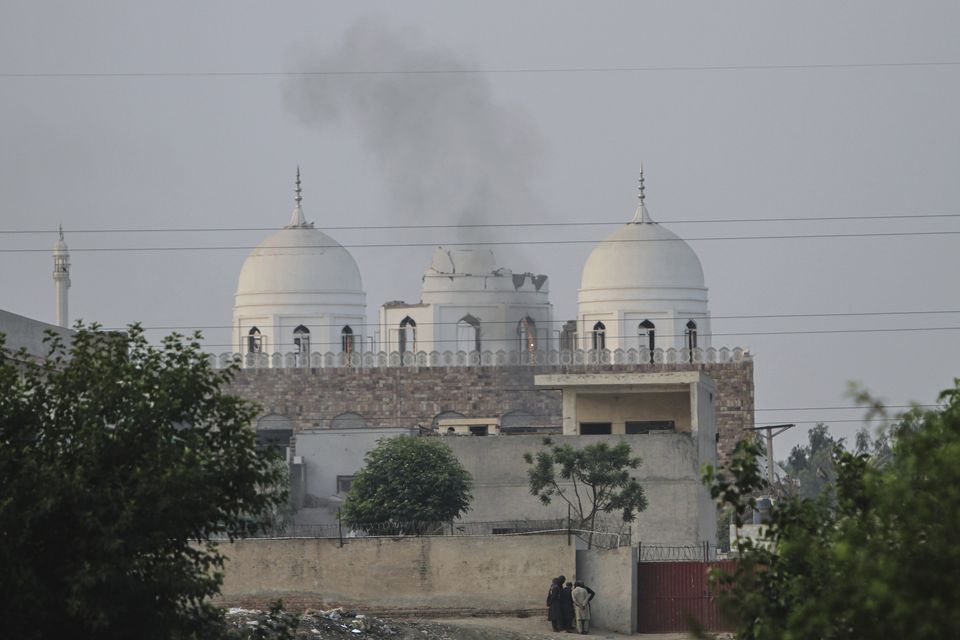 Local residents stand outside a mosque of an Islamic seminary partially damaged by a suspected Indian missile attack (Asim Tanveer/AP)