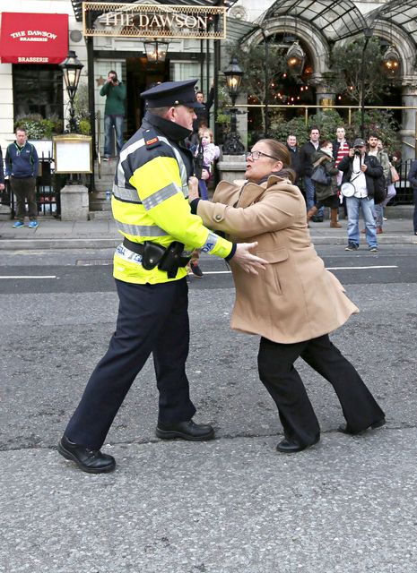 A garda tries to restrain a protester at the Mansion House yesterday where Taoiseach Enda Kenny was heckled