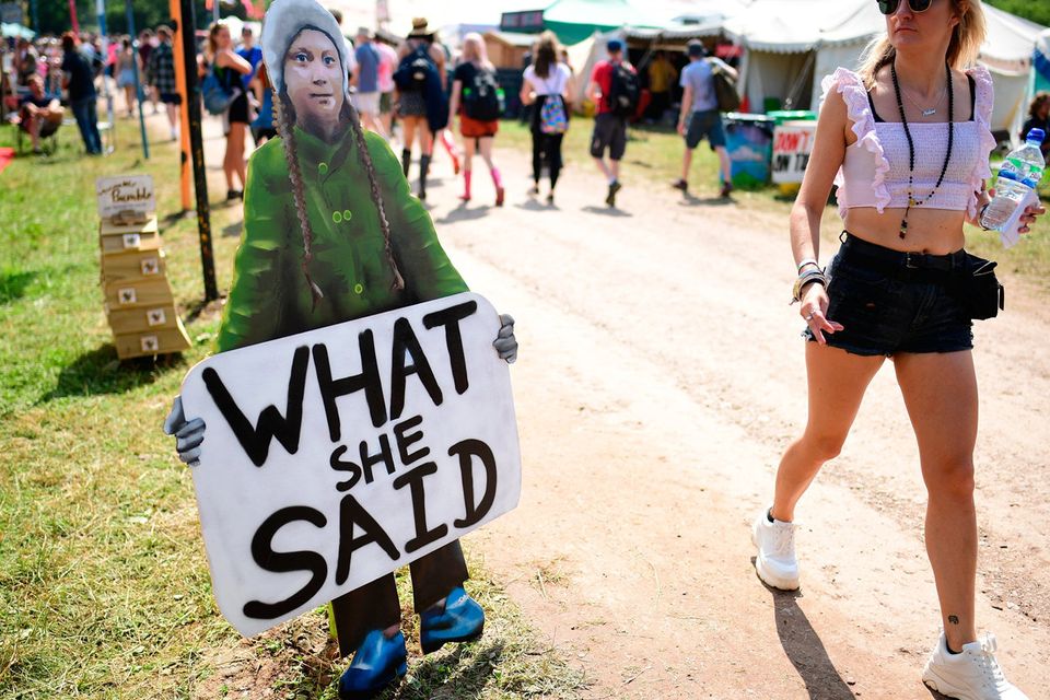 GLASTONBURY, ENGLAND - JUNE 26: A festival-goer passes a picture of young Swedish climate activist Greta Thunberg during day one of Glastonbury Festival at Worthy Farm, Pilton on June 26, 2019 in Glastonbury, England. (Photo by Leon Neal/Getty Images)