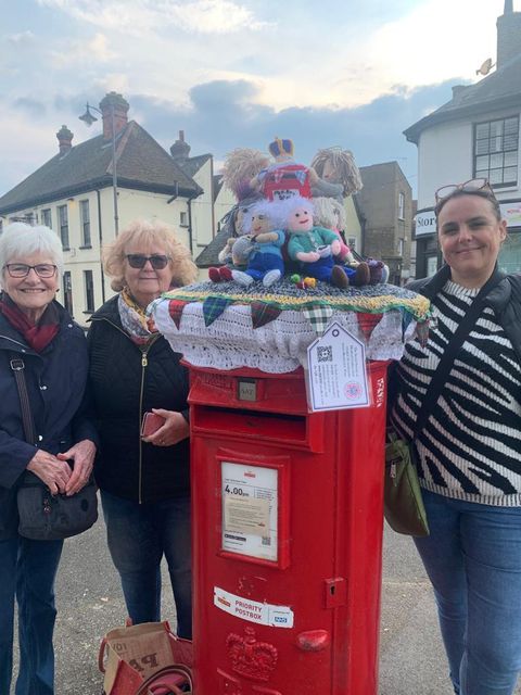 Jill Harris, Irene Getley and Sarah Edwards with a postbox topper they made which shows members of the group putting up a topper (Secret Society of Hertford Crafters/PA)