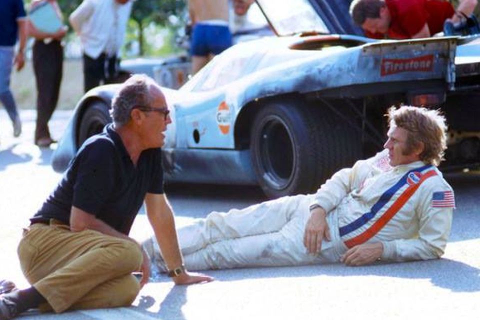 Steve McQueen relaxes during a break in filming of Le Mans with original director John Sturges, who later quit mid-production