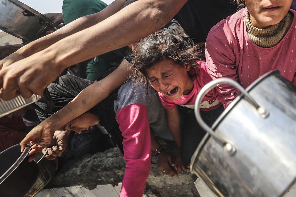 Displaced Palestinians, including children, wait with empty pots to receive food. Photo: Mahmoud Issa/Anadolu via Getty.