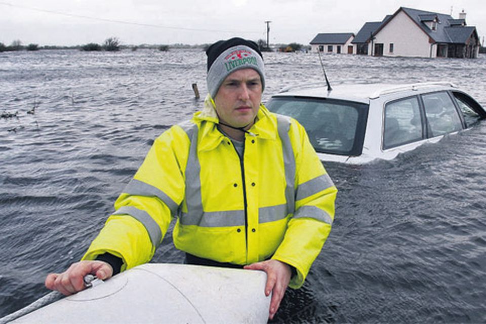 Liam Kehoe waist deep in water with his new house flooded in the backround at Caherlea, near Claregalway, Co Galway, yesterday