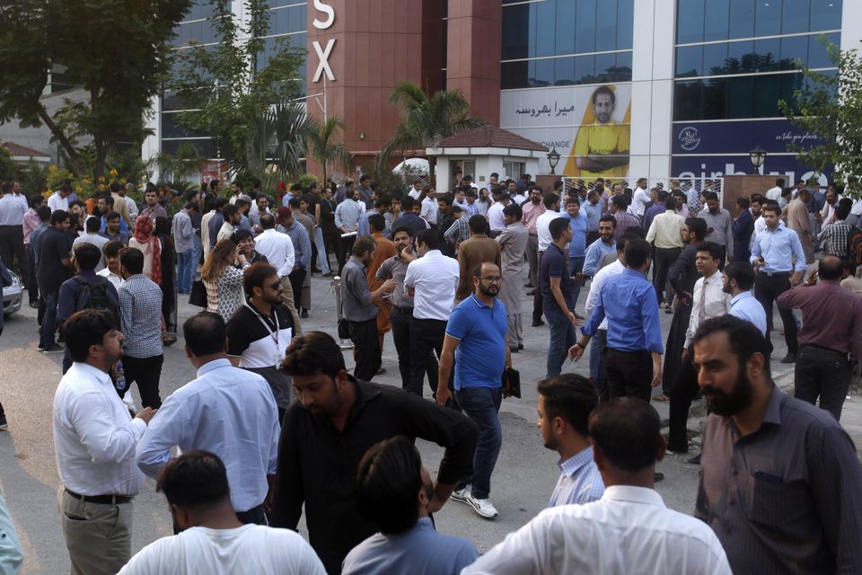 People stand outside their office after an earthquake is felt in Islamabad (AP Photo/Anjum Naveed)