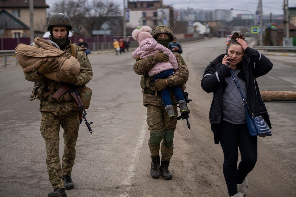 Ukrainian soldiers carry children to help a family fleeing on the outskirts of Kyiv yesterday. Picture by Emilio Morenatti/AP