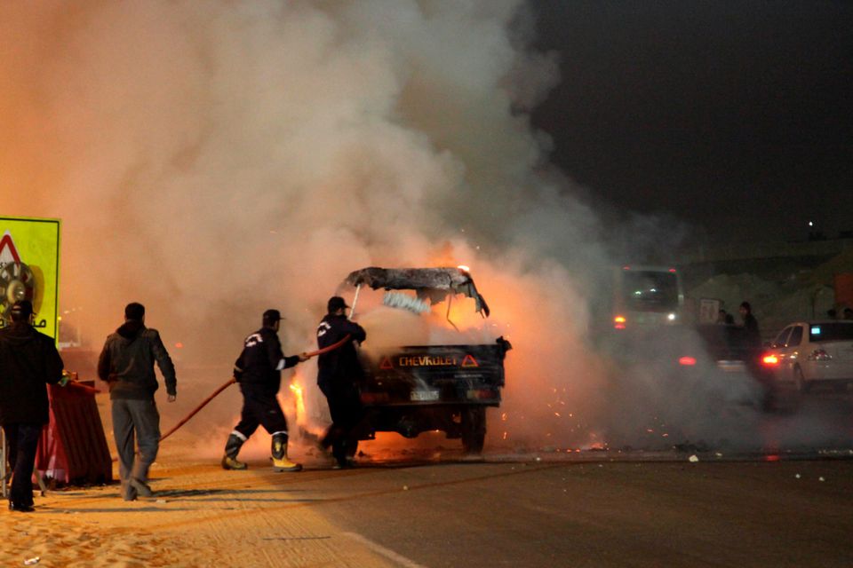 Egyptian firefighters extinguish fire from a vehicle outside a sports stadium in a Cairo's northeast district, on February 8, 2015 during clashes between supporters of Zamalek football club and security forces