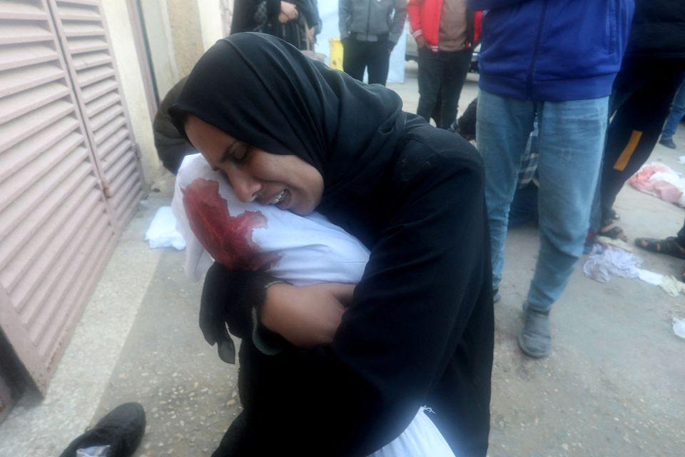 A woman in Gaza holds the body of a child killed in Israeli strikes. Photo: Reuters