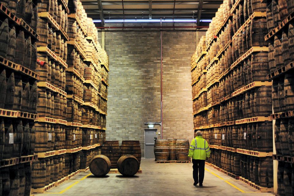 An employee passes American oak barrels containing Jameson whiskey, produced by Irish Distillers, in Middleton, a distillery believed to be operating at, or close to, capacity now