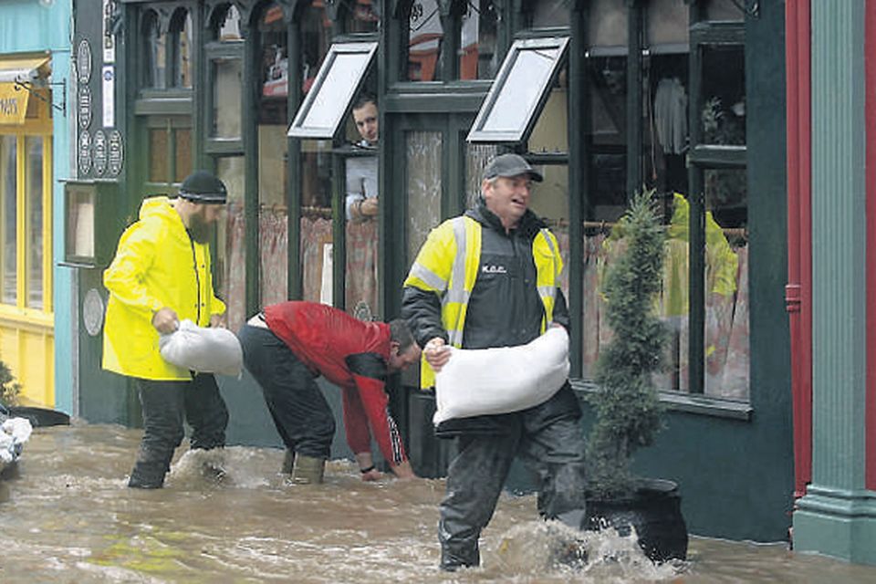 Council workers place sandbags outside shops in Kenmare after the River Finnihy burst its banks and flooded the town.