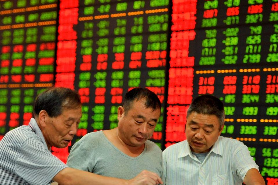 Investors look at a computer screen in front of an electronic board showing stock information at a brokerage house in Fuyang, Anhui province, China. Photo: Reuters