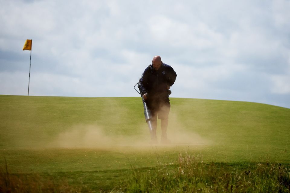 A member of the groundstaff clears the orange powder from the 17th green following a Just Stop Oil protest during the second round