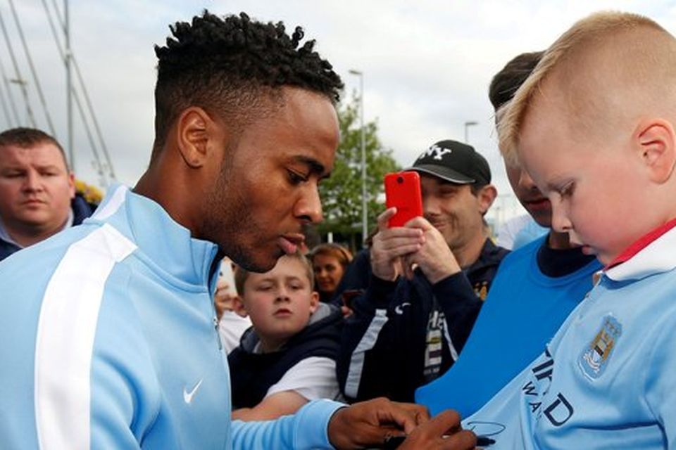 New Manchester City signing Raheem Sterling signs autographs for supporters as he leaves the club's Etihad Stadium in Manchester