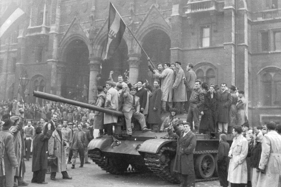 A group of men hold a flag on top of a tank in front of the Parliament building in Budapest during the Hungarian Revolt of 1956. Photo by Hulton Archive/Getty Images